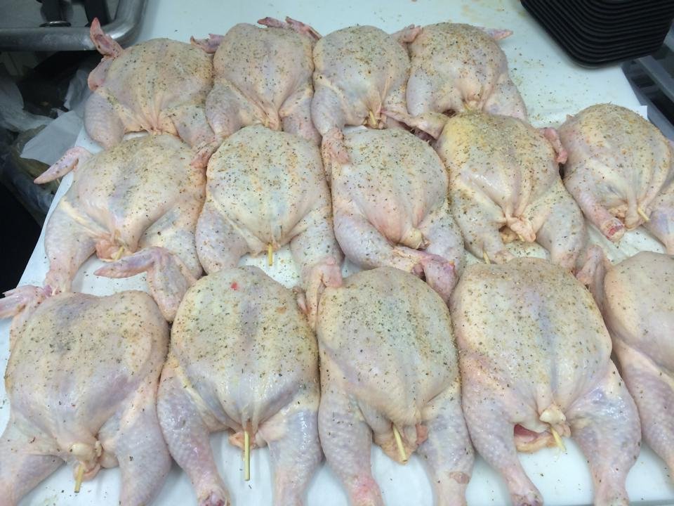 1459824_721626307928986_8266556176612911930_n Raw seasoned chickens arranged neatly on a cutting board, ready for cooking or preparation in a professional kitchen.