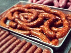 Horrmann+Meats,+Missouri+-+sausages Assorted freshly made sausages displayed on a metal tray, featuring various shapes and colors, highlighting the craftsmanship of artisanal sausage making.